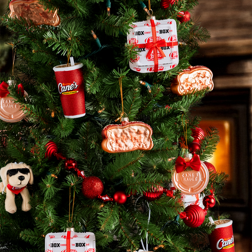 Decorative Christmas tree with various ornaments including lemonade cup, box combo, Cane's sauce, Texas toast, and Cane plush.