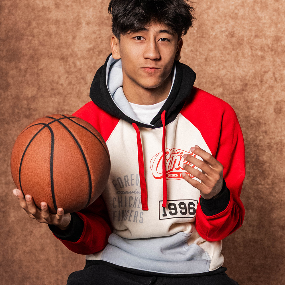 Model wearing Forever Craving Chicken Fingers Hoodie and holding a basketball