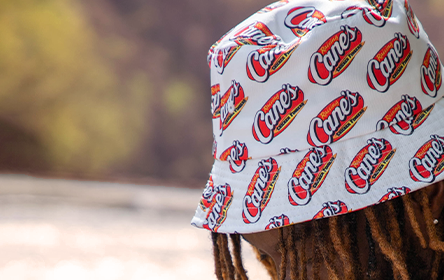 Person wearing white bucket hat with Cane's logo pattern