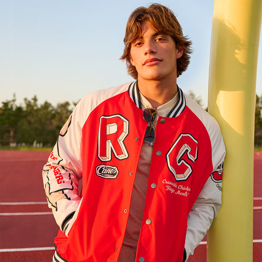 Model wearing Raising Cane's Varsity Raglan Jacket, showing front of item