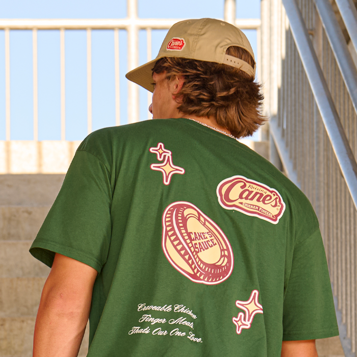 Model wearing Raising Cane's Varsity Tee, showing back of item