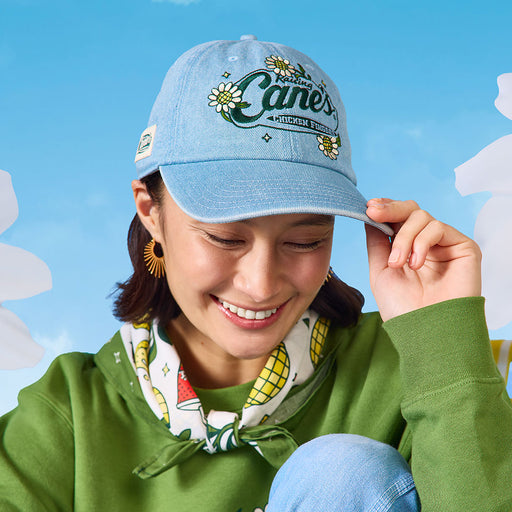 Woman model wearing the Cane’s Floral Denim Hat in blue featuring a floral pattern and Cane’s branding