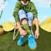 Person sitting on a lemon-shaped chair wearing green socks with cartoon characters and blue sneakers, surrounded by lemon slices and flowers
