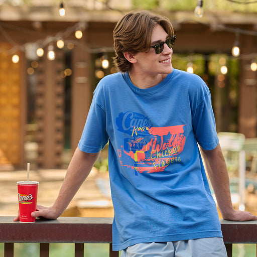 Man wearing blue tee with Cane's logo and designs, facing towards camera